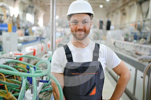 Smiling and happy employee. Industrial worker indoors in factory. Young technician with hard hat