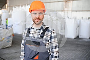 Smiling and happy employee. Industrial worker indoors in factory. Young technician with hard hat