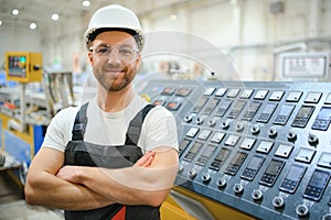 Smiling and happy employee. Industrial worker indoors in factory. Young technician with hard hat
