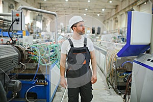 Smiling and happy employee. Industrial worker indoors in factory. Young technician with hard hat