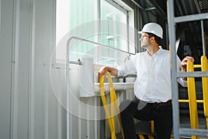 Smiling and happy employee. Industrial worker indoors in factory. Young technician with white hard hat