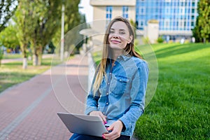 Smiling happy girl in jeans shirt using laptop for communication