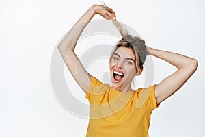 Smiling happy girl pull her hair and laughing, concept of healthy and stong hair, haircare product and cosmetics