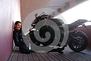 Smiling happy girl is sitting in tunnel near her motobike