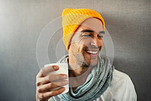 Smiling and happy handsome young man drinking coffee, tea, water, with white mug.