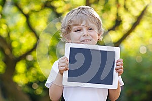 Smiling happy little child holding tablet pc, outdoors