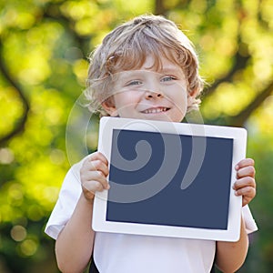 Smiling happy little child holding tablet pc, outdoors