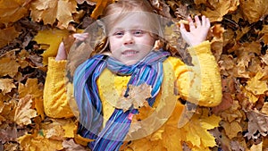 Smiling happy little girl lying on the autumn leaves