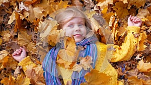 Smiling happy little girl lying on the autumn leaves
