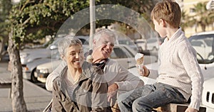 Smiling, happy and loving grandparents and grandson eating ice cream on a fun day. Mature couple and child smiling and