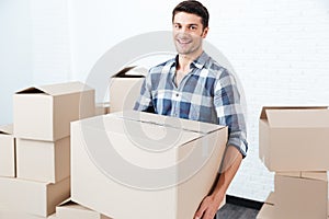 Smiling happy man carrying carton boxes at new flat