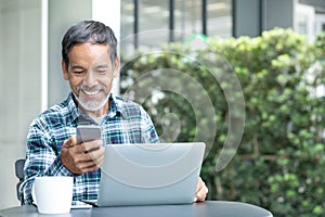 Smiling happy mature man with white stylish short beard using smartphone gadget serving internet