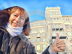 Smiling happy mature middle aged Woman taking selfie and Giving Thumbs Up in Front of old Building in tour in city on a