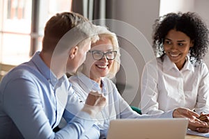 Smiling mature female mentor executive talking at diverse group meeting
