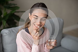 Smiling happy millennial woman taking daily vitamins.