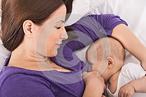 Smiling happy mother breastfeeding her baby infant