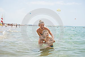 Smiling and happy mother and her son playing and running on the beach. Concept of friendly family