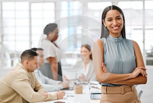 Smiling, happy and motivated young business woman with arms crossed showing great leadership to her team in an office