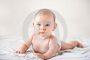 Smiling happy newborn infant baby tummy time on bed bright airy copy space childhood