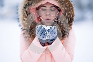 Smiling happy pretty woman in warm winter jacket outdoors enjoys winter journey, weared gloves and hood, a lot of snow