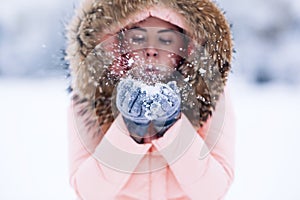 Smiling happy pretty woman in warm winter jacket outdoors enjoys winter journey, weared gloves and hood, a lot of snow