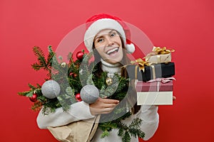 Smiling happy pretty young woman holding bouquet of spruce branches and present boxes celebrating new year, christmas gifts,