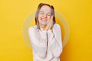 Smiling happy relaxing teenage girl in jumper with ponytails isolated over yellow background enjoying weekend nap leaning on her