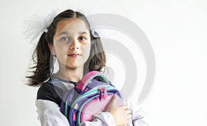 Smiling happy schoolgirl. cute caucasian girl with brown hair with two big bows in her hair holds backpack with school