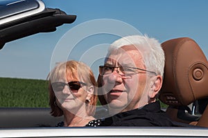 Smiling happy senior couple in sports car