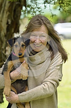 Smiling happy senior woman case of puppy love holding baby dog