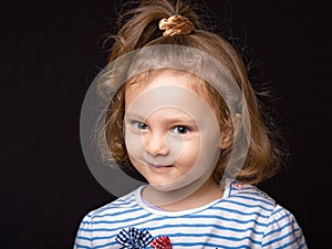 Smiling happy  small kid girl with grimacing face looking and deciding the question on black studio background. Closeup