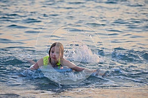 A smiling, happy teenage girl is swimming in the sea or pool on an inflatable ring.