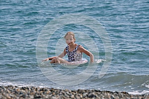 A smiling, happy teenage girl is swimming in the sea or pool on an inflatable ring.