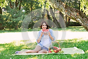 Smiling happy woman eating a watermelon in the park
