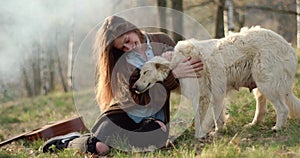 Smiling happy woman gently stroking white dog around fire place.real friends people outdoor camping tent vacation in