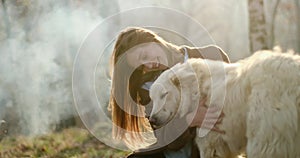 Smiling happy woman gently stroking white dog around fire place.real friends people outdoor camping tent vacation in