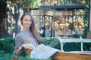 Smiling happy woman sitting on the bench in the city