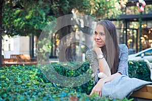 Smiling happy woman sitting on the bench in the city