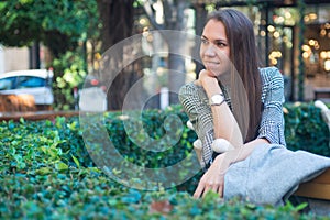 Smiling happy woman sitting on the bench in the city