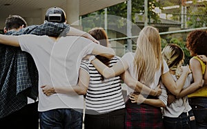 Smiling happy young adult friends arms around shoulder outdoors