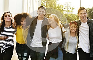 Smiling happy young adult friends arms around shoulder walking o