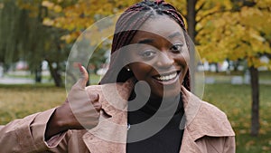 Smiling happy young african american woman looking at camera showing thumbs up giving service recommendation give