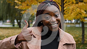 Smiling happy young african american woman looking at camera showing thumbs up giving service recommendation give