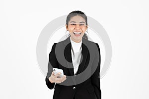 Smiling happy young Asian business woman in suit holding mobile smart phone over white isolated background