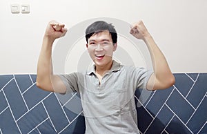 a smiling happy young asian man is excited and celebrating win and success