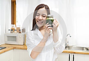 Smiling happy young Asian woman drinking fresh raw green detox vegetable juice at home. Healthy Food Eating, Diet And Lifestyle