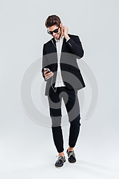 Smiling happy young businessman litening music with earphones and smartphone