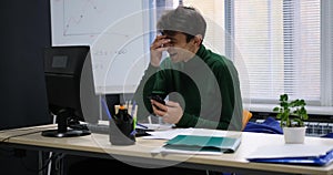 Smiling happy young caucasian man use phone at office