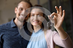 Smiling happy young married couple holding keys from new home