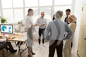 Smiling happy young and senior office workers talking in coworki